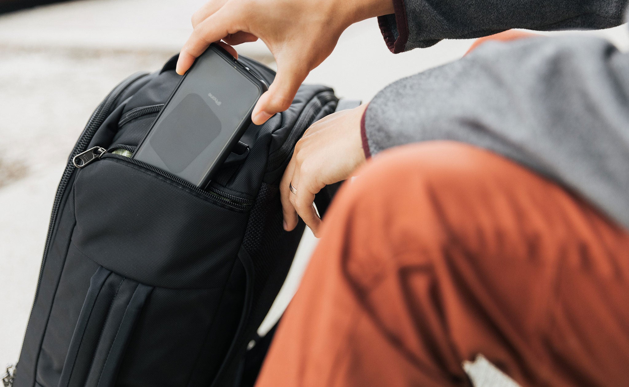 Person putting a cell phone into the smallest quick access pocket of the Techonaut