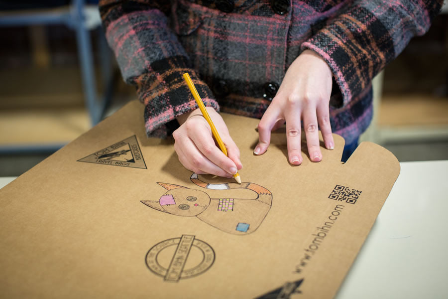 Kat drawing a patchwork cat on a shipping box